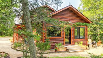 A wooden cabin with a porch, a large window, and a door.