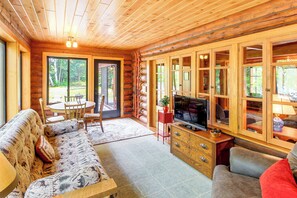 Ein Holzblockhaus-Interieur mit einer Couch, einem Fernseher und Holzausbau.