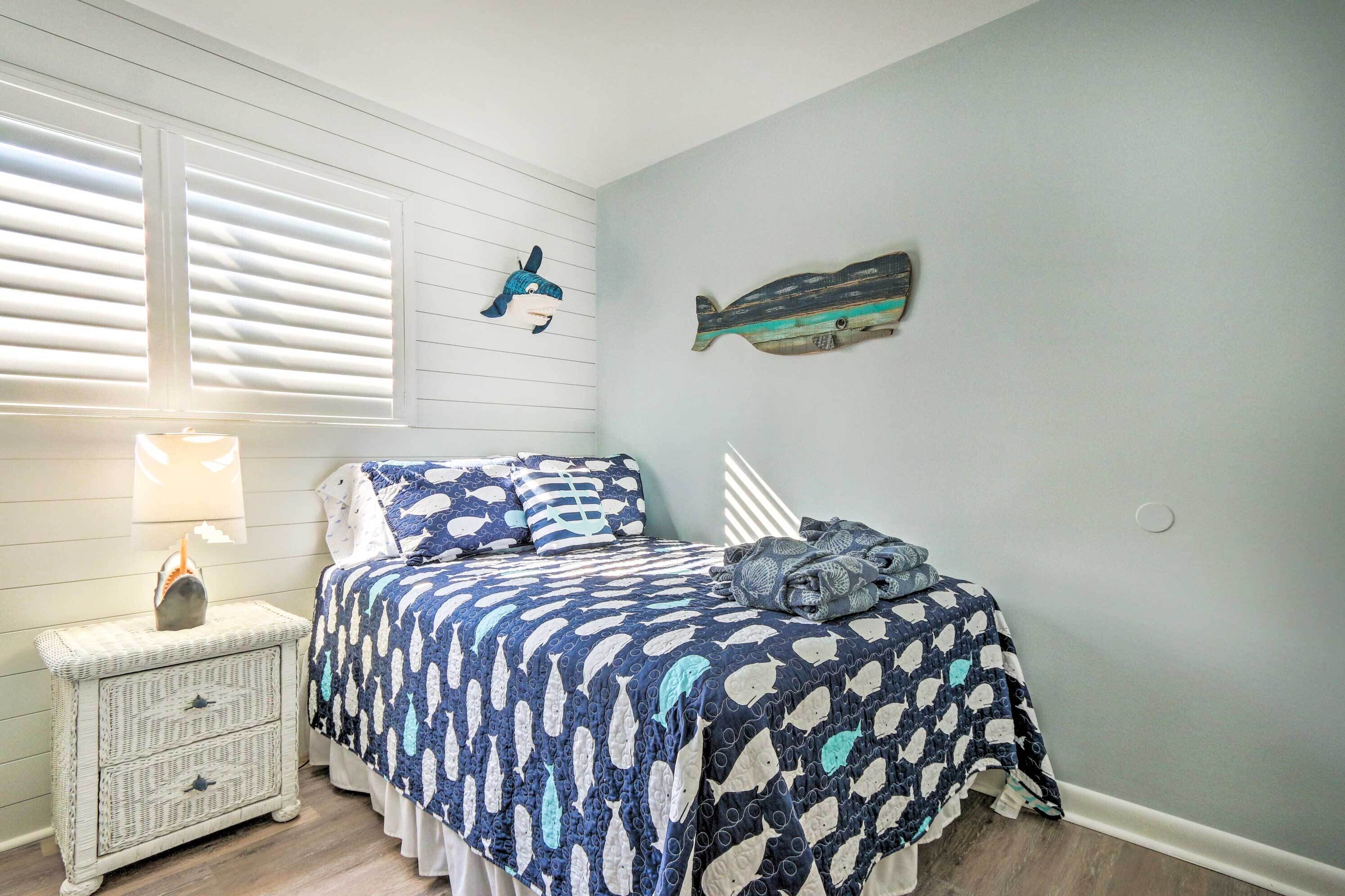 Un dormitorio con cama, mesita de noche, lámpara y adornos en la pared.