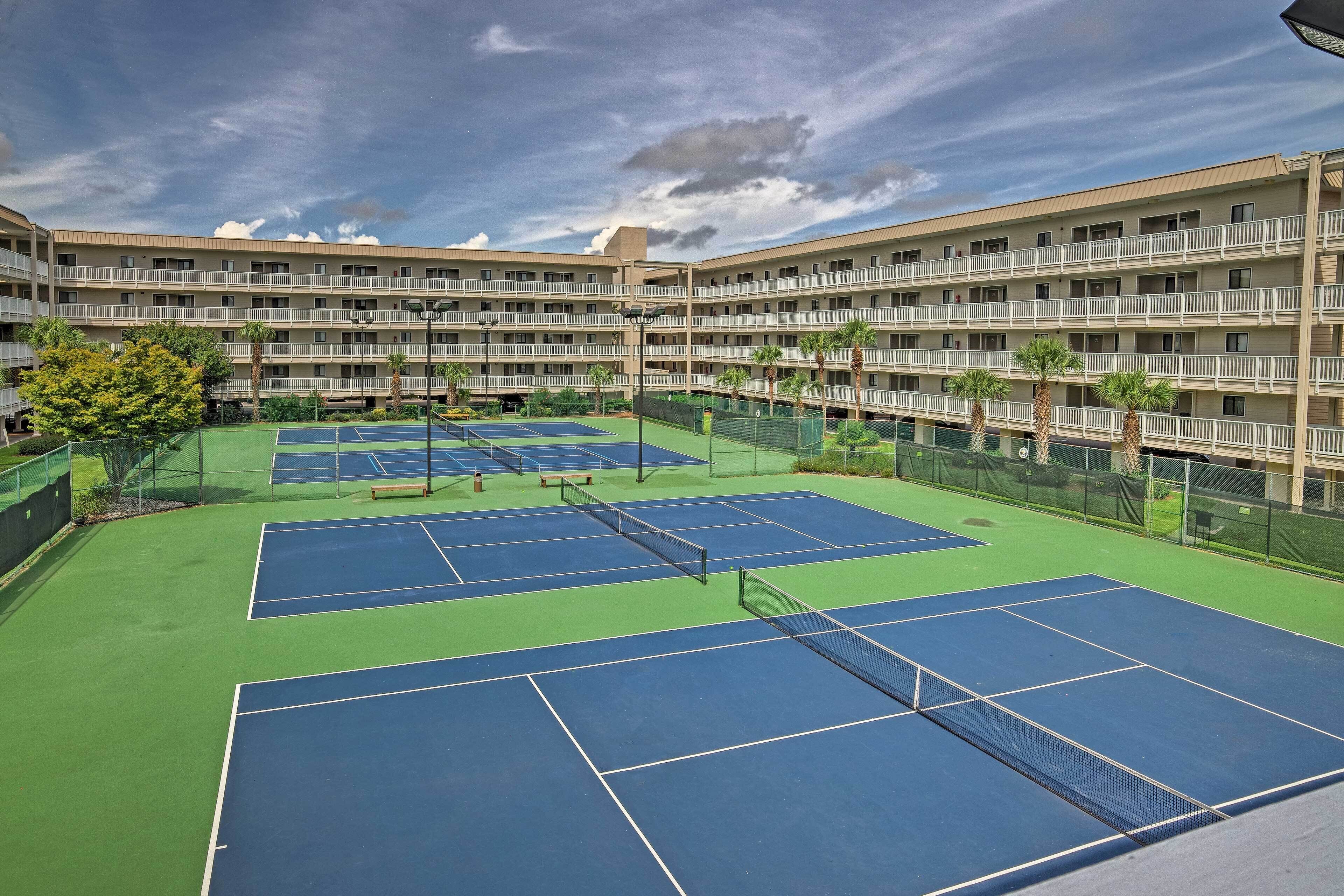 Een meerhoog hotel met een tennisterrein.