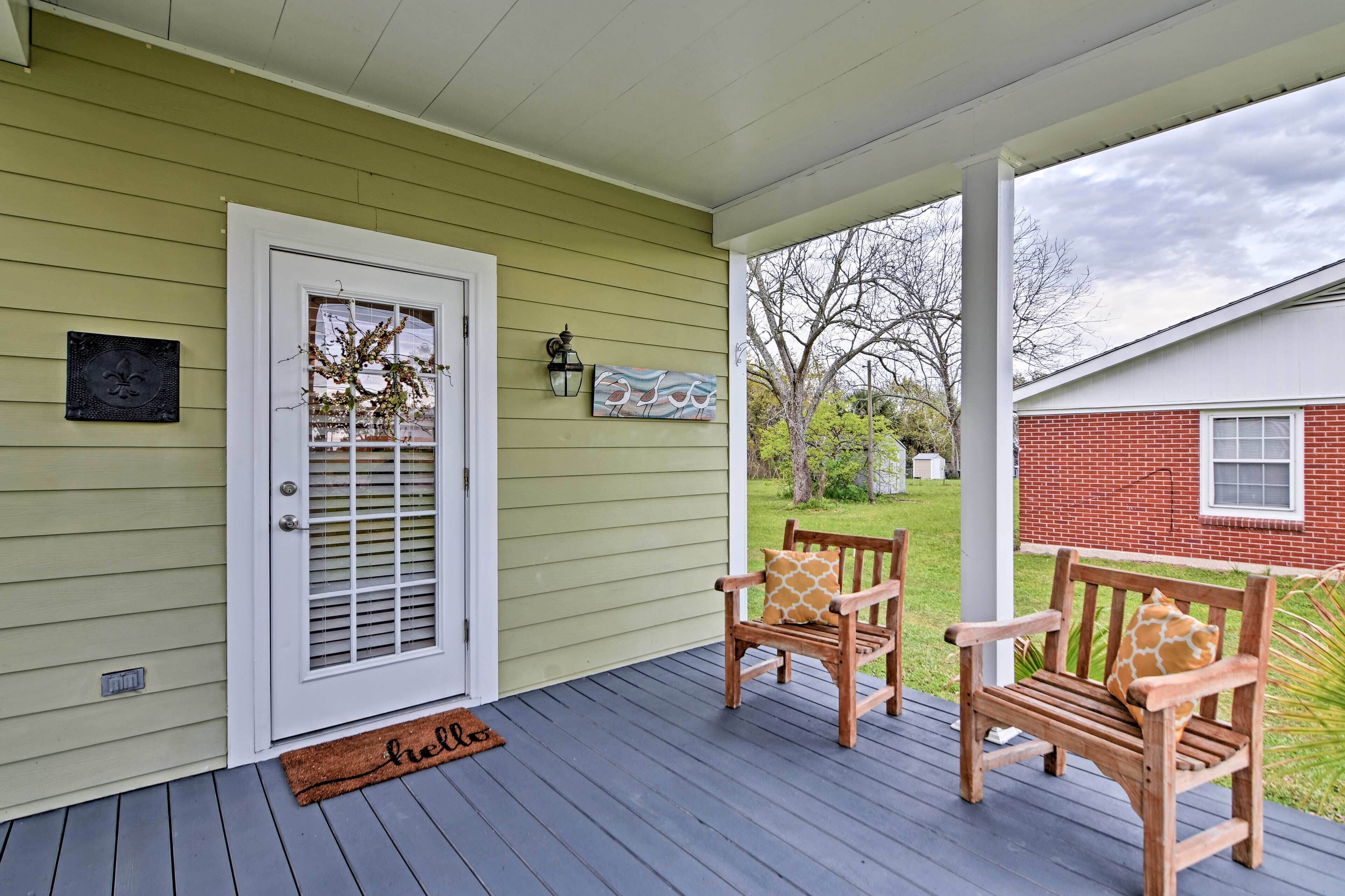 A porch with a wooden bench, a door with a window, and a doormat.
