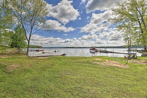 A lakeside view with docked boats, grassy areas, and trees. - Lakefront Gloversville Home w/ Beach + Dock! (Gloversville)