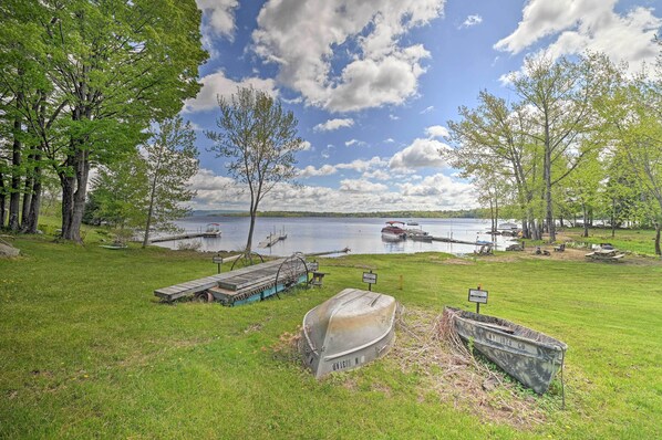 A lakeside park with a dock, boats, and a grassy area.