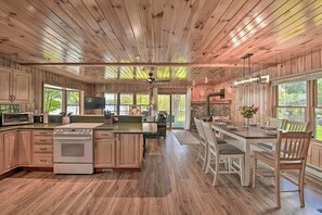 A spacious kitchen with wooden cabinets, a central island, and a dining area with a large table and chairs. - Lakefront Gloversville Home w/ Beach + Dock! (Gloversville)