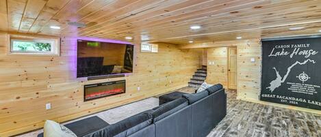 A log cabin interior with a fireplace, a TV mounted on the wall, and a sign indicating the property name.