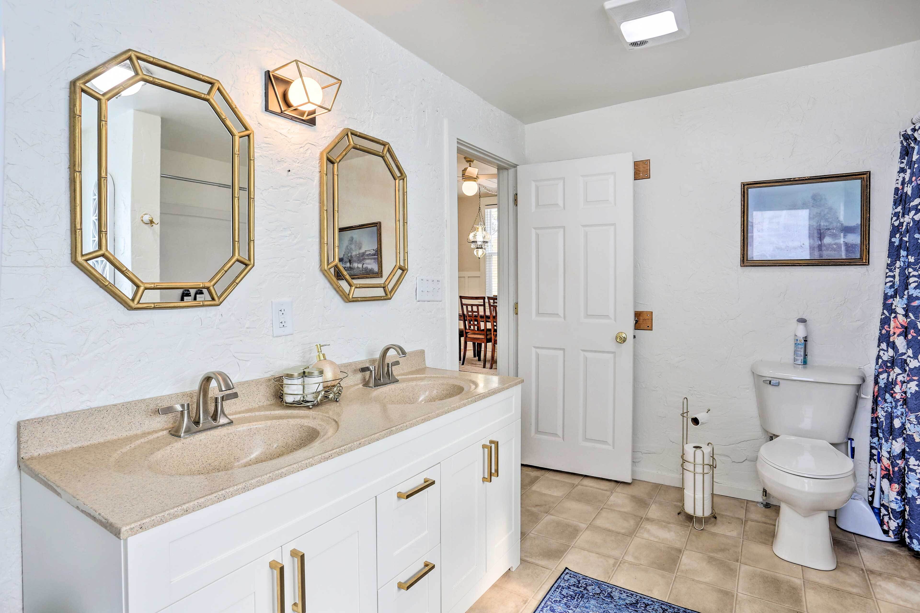 Une salle de bain avec deux lavabos, des toilettes et un rideau de douche.