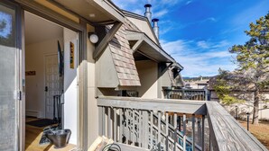 A wooden deck with a railing, a door leading inside, and a metal bucket on the floor. - Walk to Winter Park Bus From Fraser Condo! (Fraser)