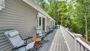 A covered deck with outdoor furniture and a railing.