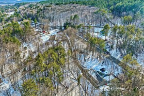 An aerial view of a forested area with a small cabin and a bridge.