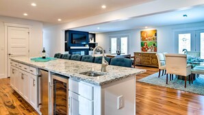 A modern kitchen with a central island, built-in appliances, and a dining area with a chandelier.