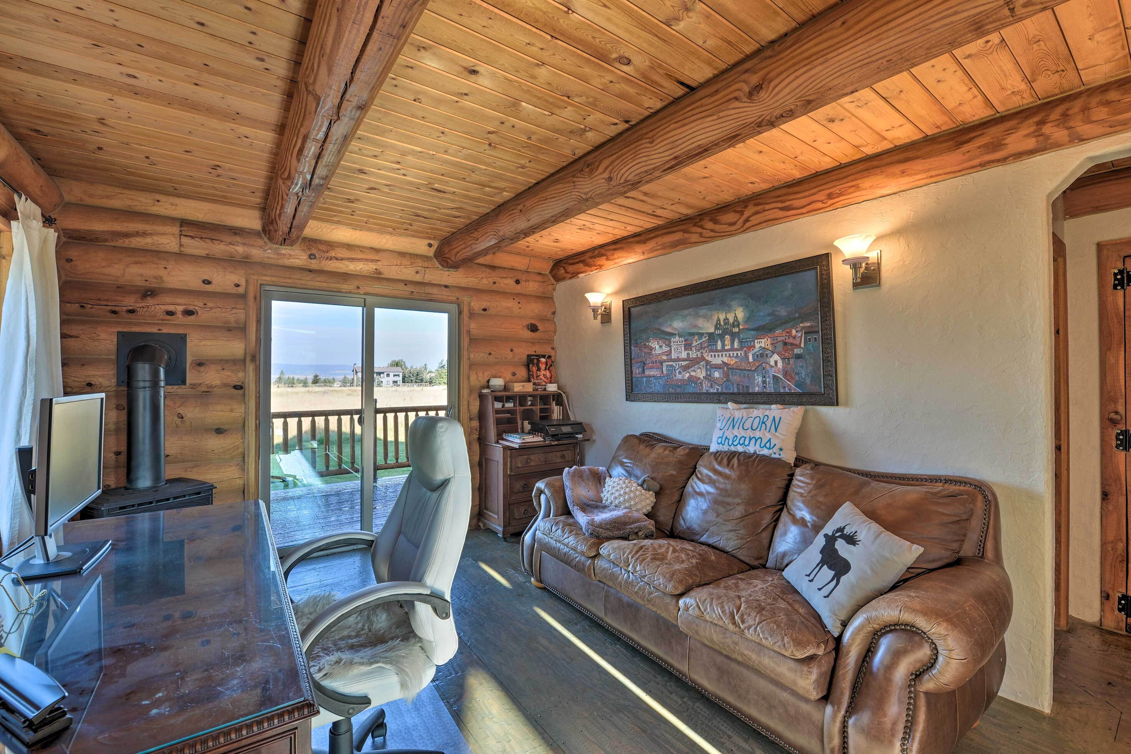 A wooden interior with a leather sofa, a glass table, and a fireplace.