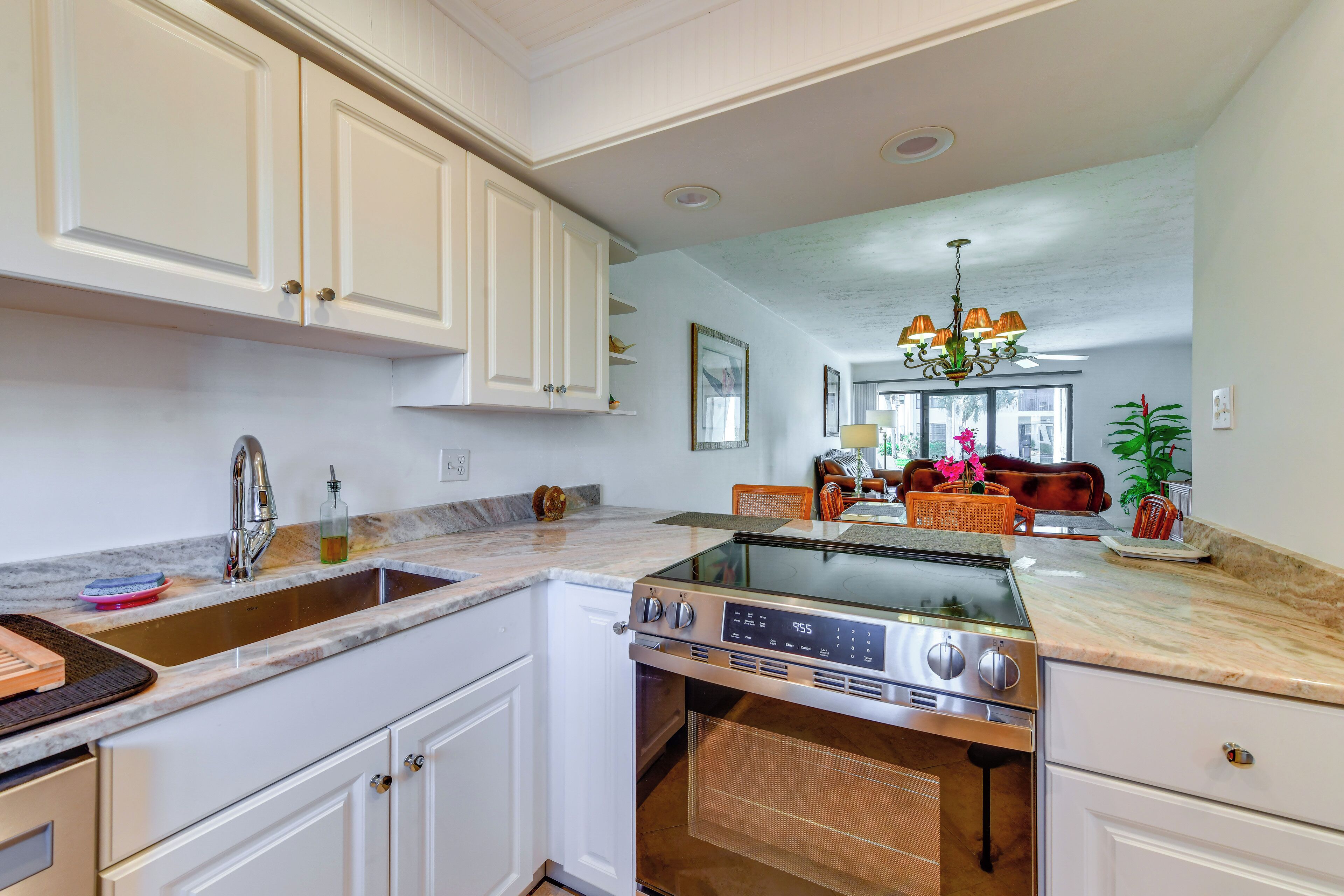 A kitchen with white cabinets, a stainless steel stove, and a large window.