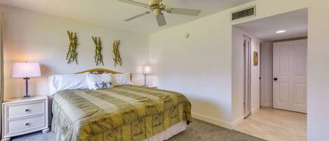 A bedroom with a bed, nightstands, a ceiling fan, and a door.