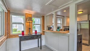A kitchen with a wooden table, a refrigerator, and a window with blinds. - Near Hiking + Dining: Dtwn Sylva Cottage! (Sylva)