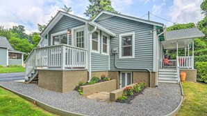 A two-story house with a front porch, a small deck, and a gravel driveway. - Near Hiking + Dining: Dtwn Sylva Cottage! (Sylva)