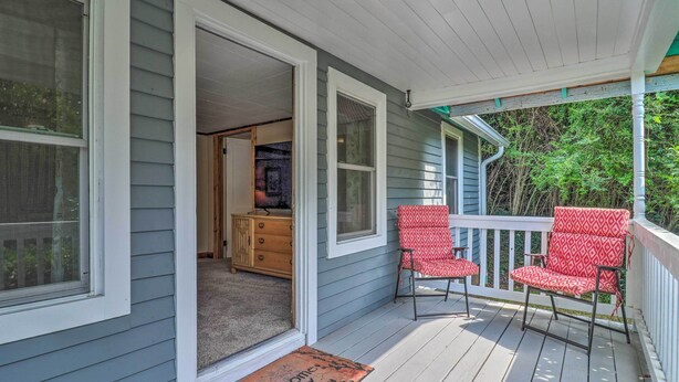A porch with a wooden deck, a red and white patterned chair, and a wooden cabinet. - Near Hiking + Dining: Dtwn Sylva Cottage! (Sylva)