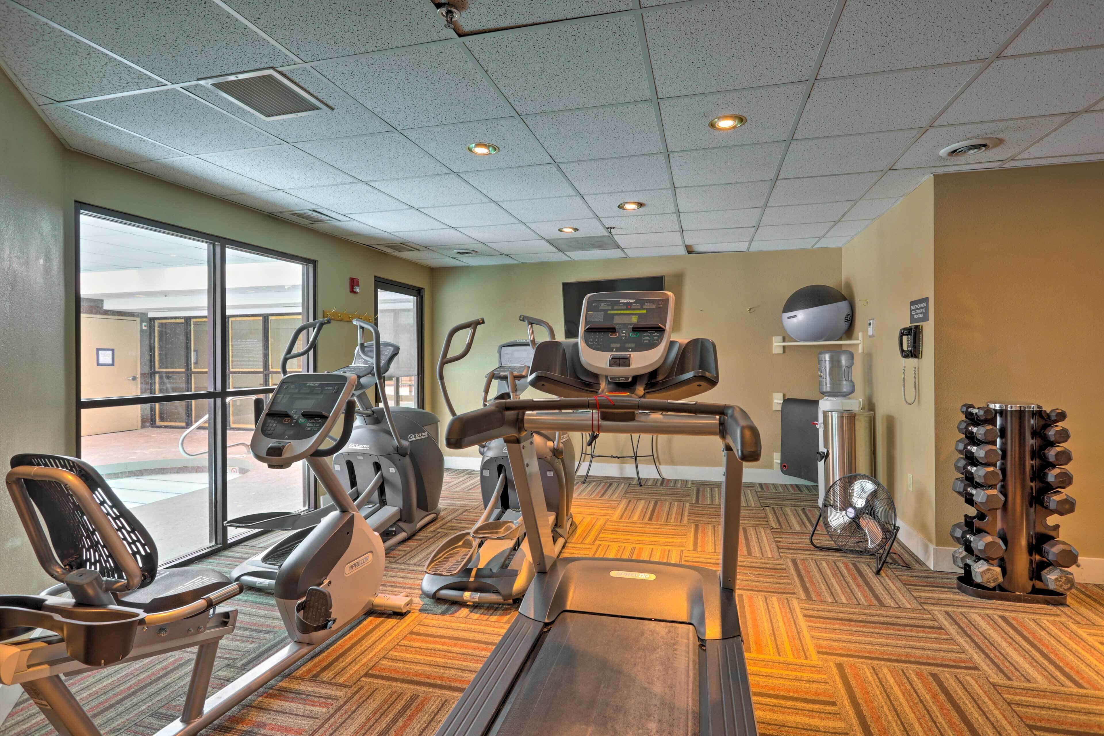 Un gimnasio con cintas de correr, elípticas y un ventilador.