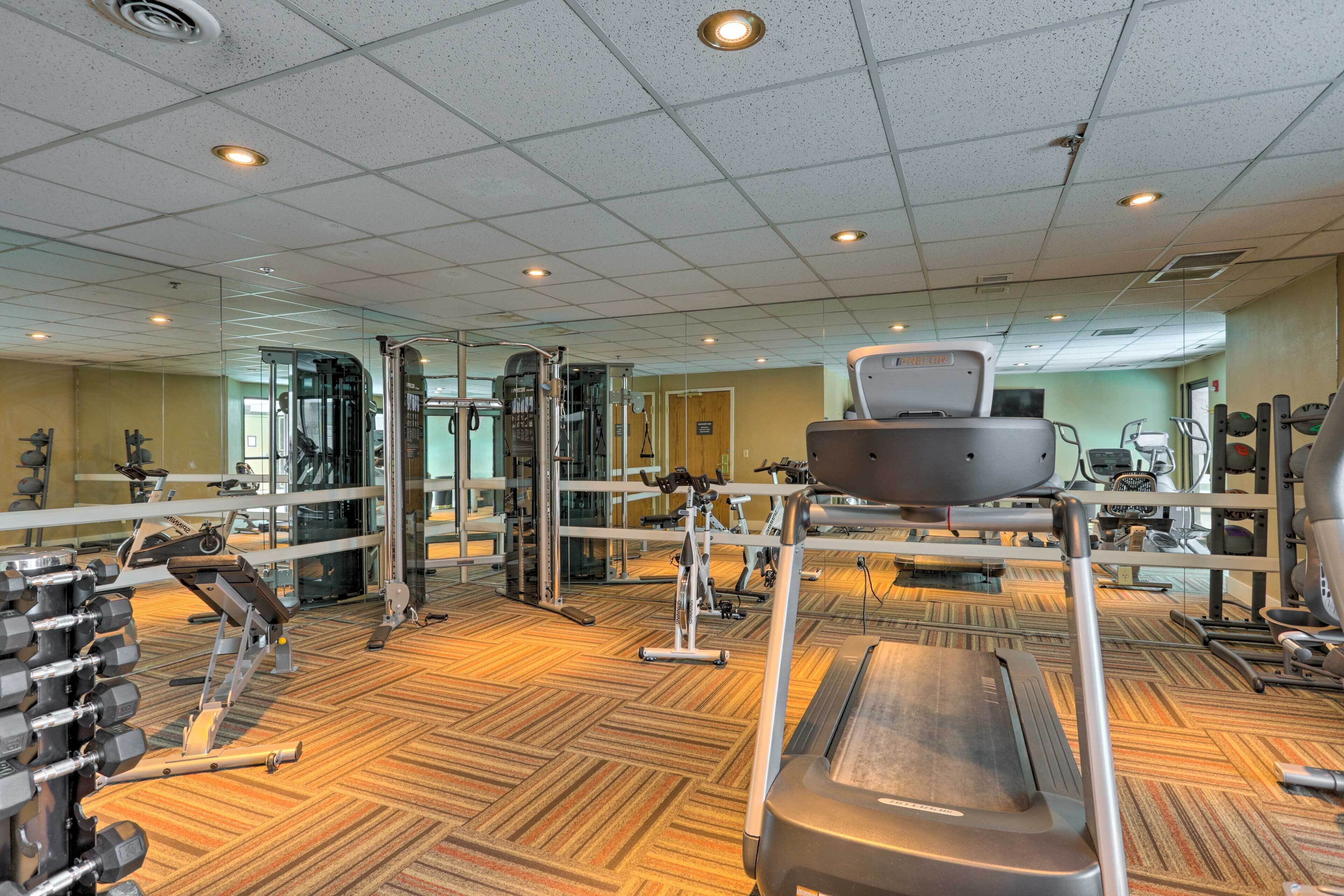 A gym with various exercise equipment, including treadmills, weight machines, and free weights.