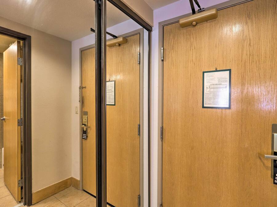 Un couloir d’hôtel avec des portes en bois, une pancarte indiquant « Veuillez ne pas déranger » et un avis affiché sur la porte de droite.