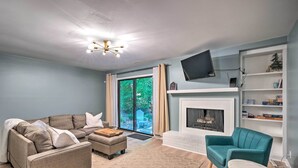 A modern living room with a sectional sofa, a teal armchair, and a fireplace. - Stylish Durham Townhome < 5 Mi to Downtown! (Durham)