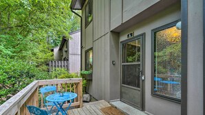 A wooden deck with blue chairs and a table, a door with a window, and a mailbox on the wall. - Stylish Durham Townhome < 5 Mi to Downtown! (Durham)