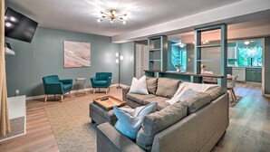 A modern living room with a sectional sofa, teal armchairs, a coffee table, and a flat-screen TV. - Stylish Durham Townhome < 5 Mi to Downtown! (Durham)