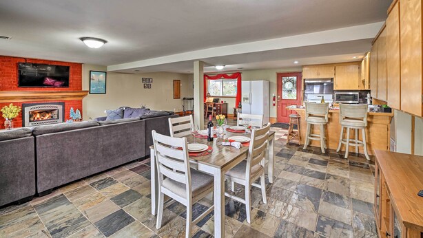 A modern living room with a fireplace, a dining area with a wooden table and chairs, and a kitchen with wooden cabinets. - Spacious Apartment on Lake Sawyer w/ Fireplace! (Black Diamond)