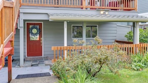 A two-story house with a front porch, a red door, and a wooden fence. - Spacious Apartment on Lake Sawyer w/ Fireplace! (Black Diamond)