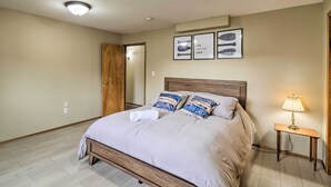 A bedroom with a wooden bed, a nightstand with a lamp, and framed artwork on the wall. - Spacious Apartment on Lake Sawyer w/ Fireplace! (Black Diamond)