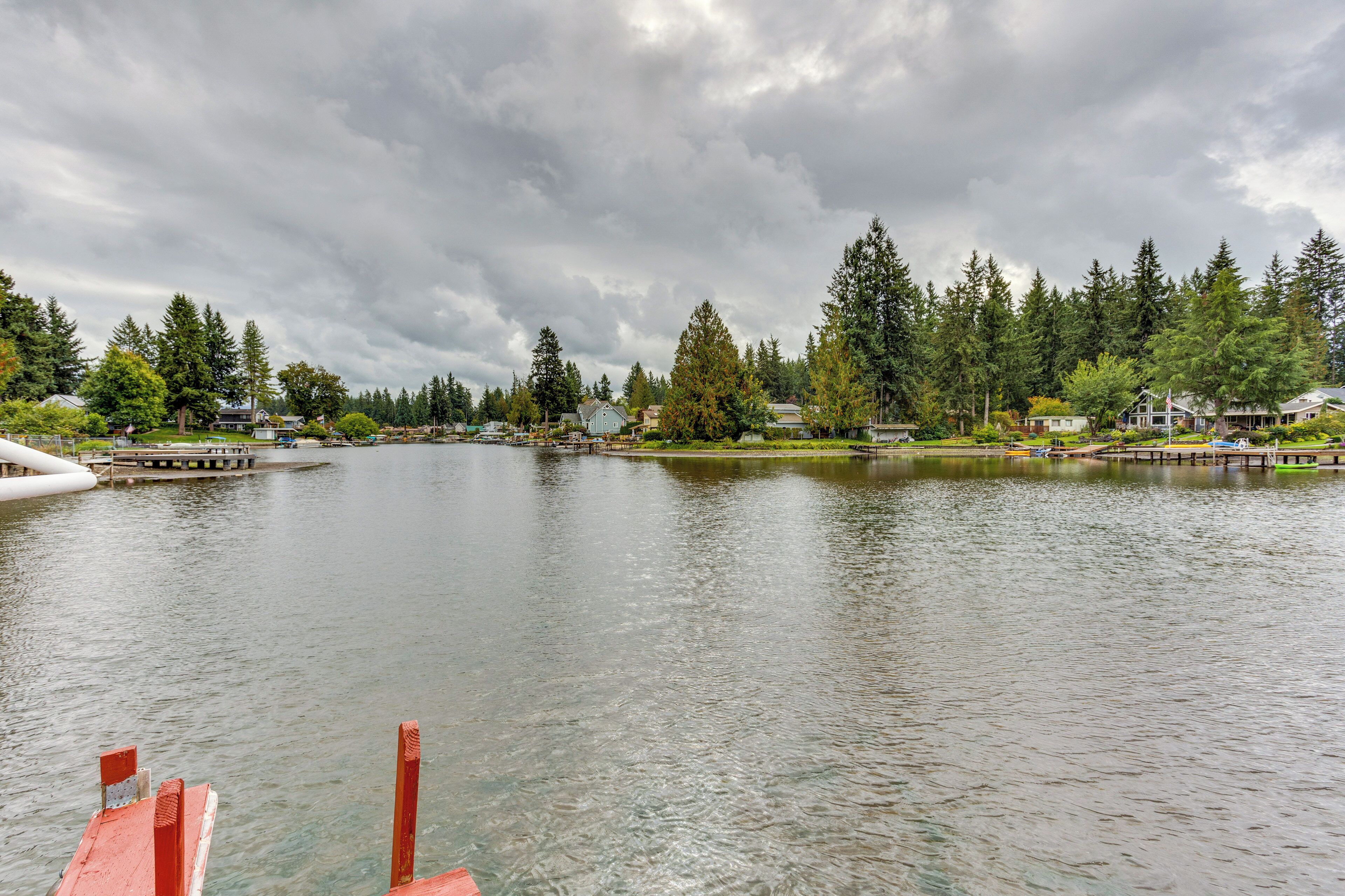 A lake with a dock, surrounded by houses and dense trees.