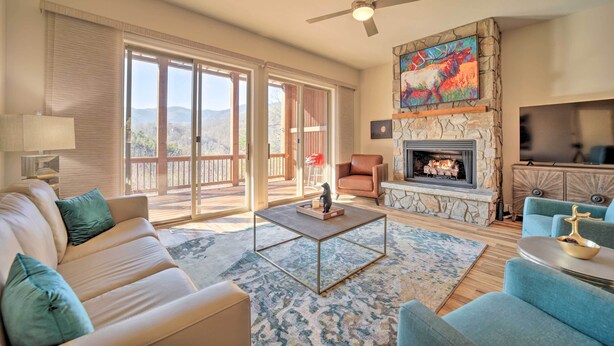 A spacious living room with a beige sofa, a coffee table, and a fireplace. - Beautiful Whittier Condo w/ Deck + Mtn Views! (Whittier)