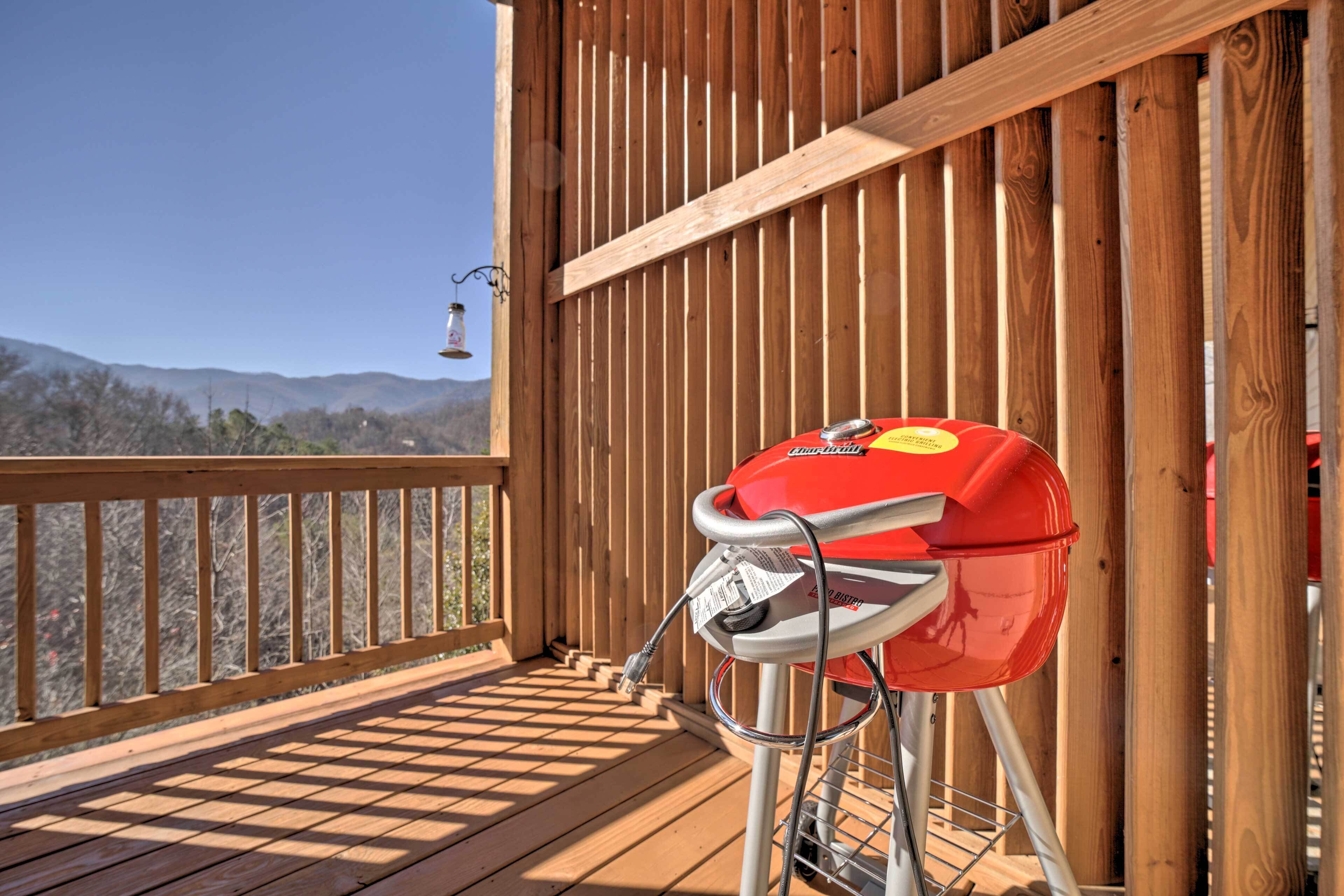 A barbecue grill on a wooden deck with a view of mountains.