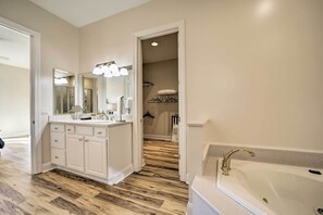 A bathroom with a double sink vanity, a bathtub, and a walk-in closet with a hanging rack. - Beautiful Whittier Condo w/ Deck + Mtn Views! (Whittier)