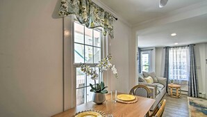 Un coin repas avec une table en bois, des chaises, un vase de fleurs et une fenêtre donnant sur l’extérieur.