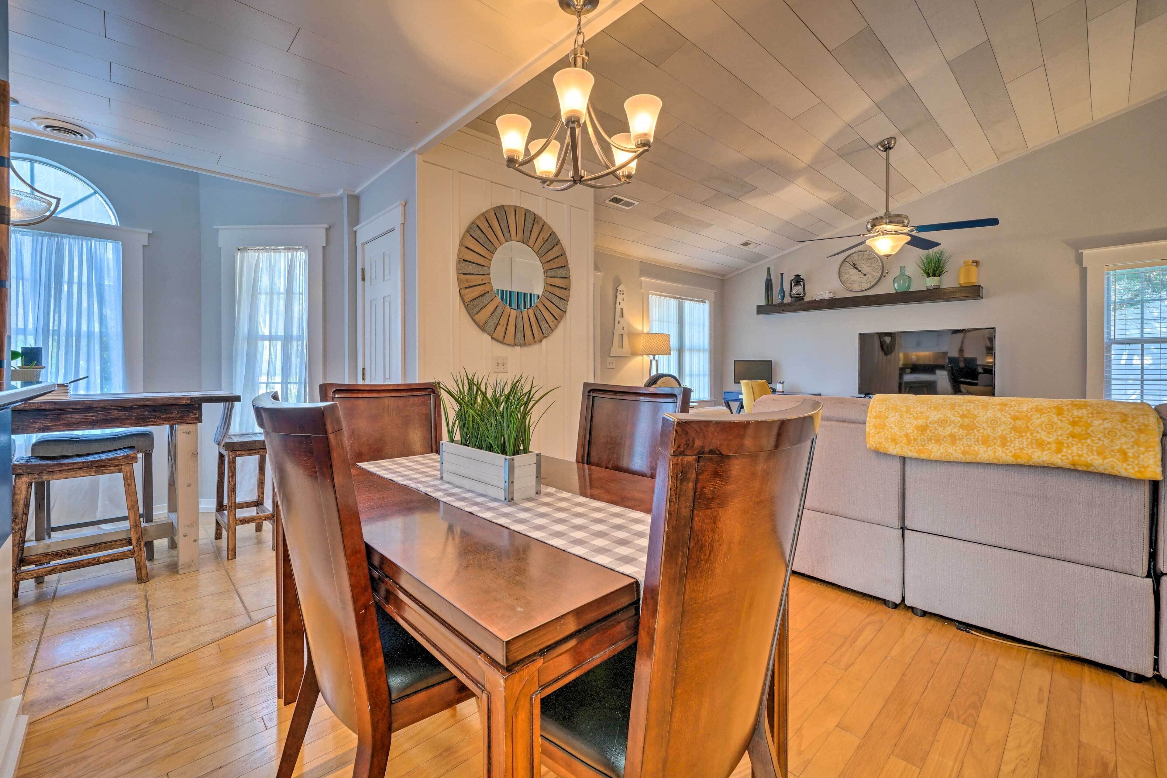 A dining area with a wooden table and chairs, a chandelier, and a large mirror on the wall.