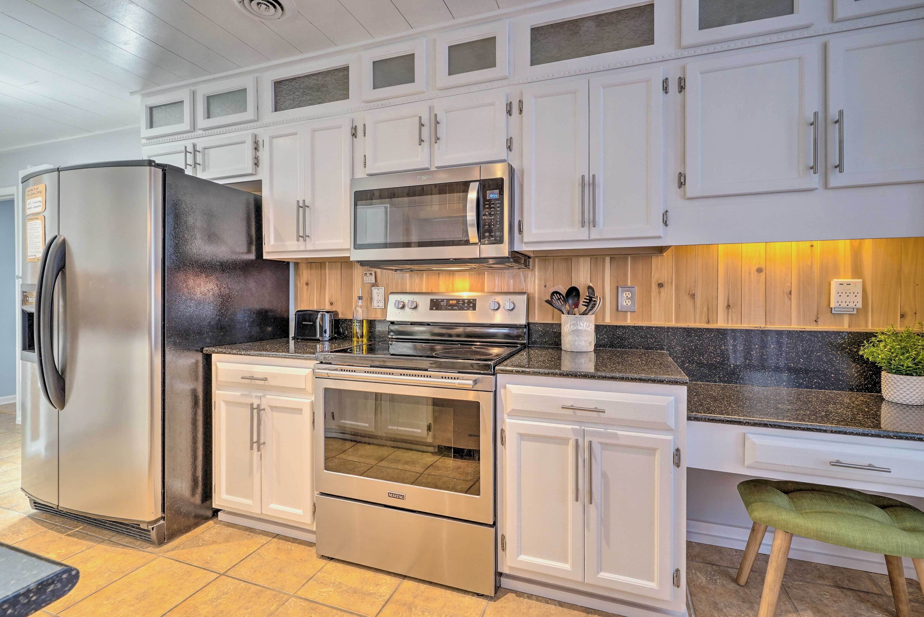A modern kitchen with white cabinets, stainless steel appliances, and a granite countertop.