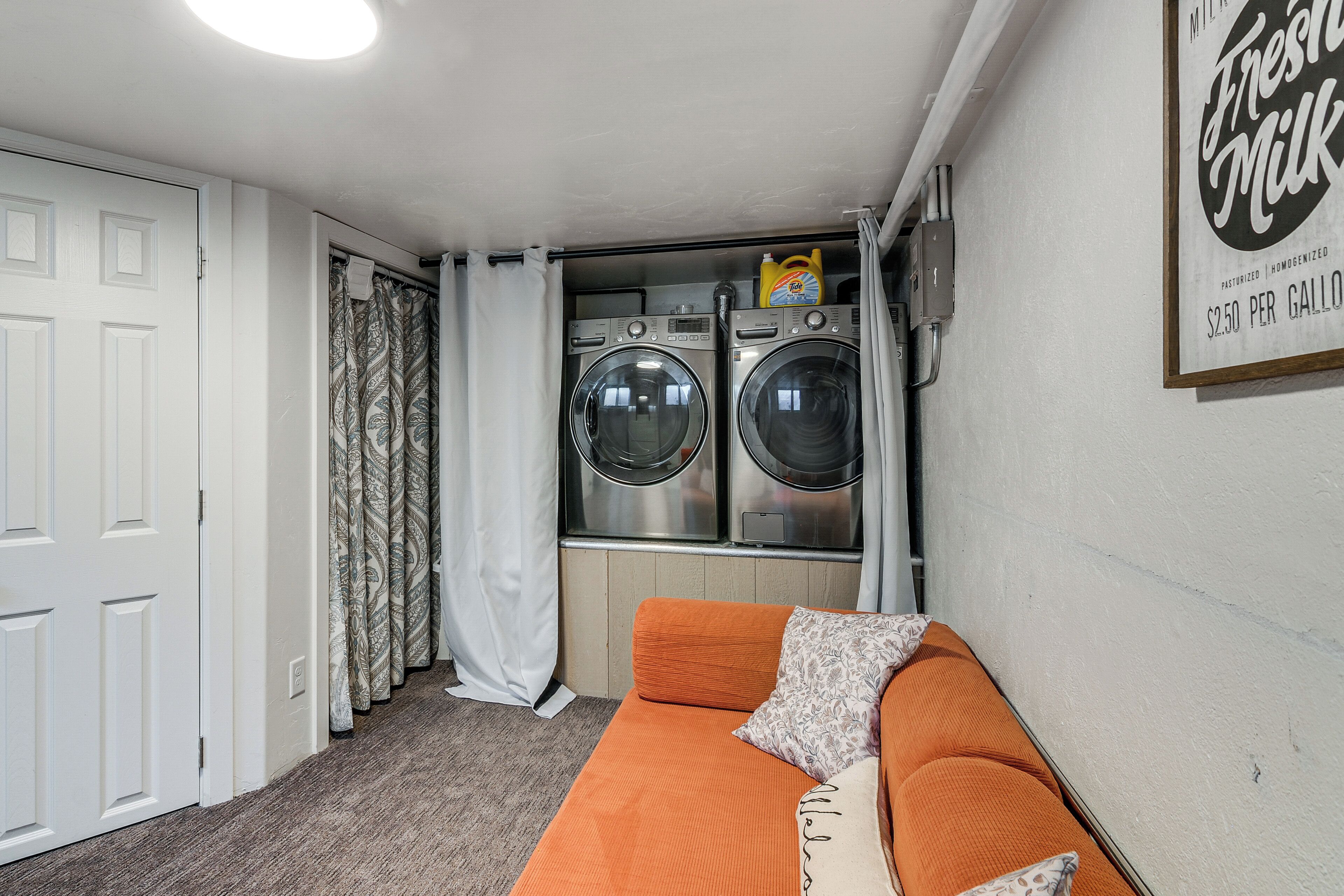 A laundry room with two washing machines, a drying machine, and a wall-mounted sign advertising fresh milk.