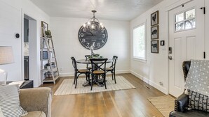 Un coin repas comprenant une table ronde, des chaises, une grande horloge murale et un lustre.
