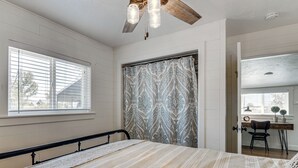 Une chambre à coucher avec un lit, une fenêtre, une porte et un ventilateur de plafond.