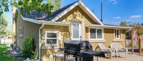Une maison avec un barbecue, un espace extérieur aménagé et un petit jardin.