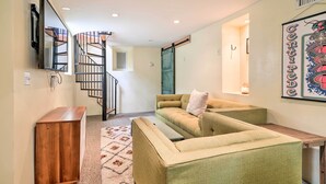 A living room with a green sofa, a wooden cabinet, and a staircase. - Charming Santa Paula Home - Walk to Downtown! (Santa Paula)