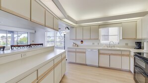 A modern kitchen with white cabinetry, a dishwasher, a stove, and a window with blinds. - Canalfront Home w/ Private Dock - 5 Mi to Beaches! (Englewood)