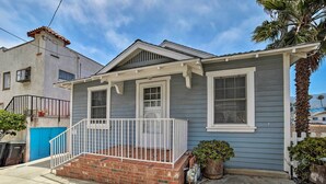 A two-story house with a front porch, a blue door, and a small garden area. - Ocean-view Home - Walk to Avalon City Center! (Avalon)