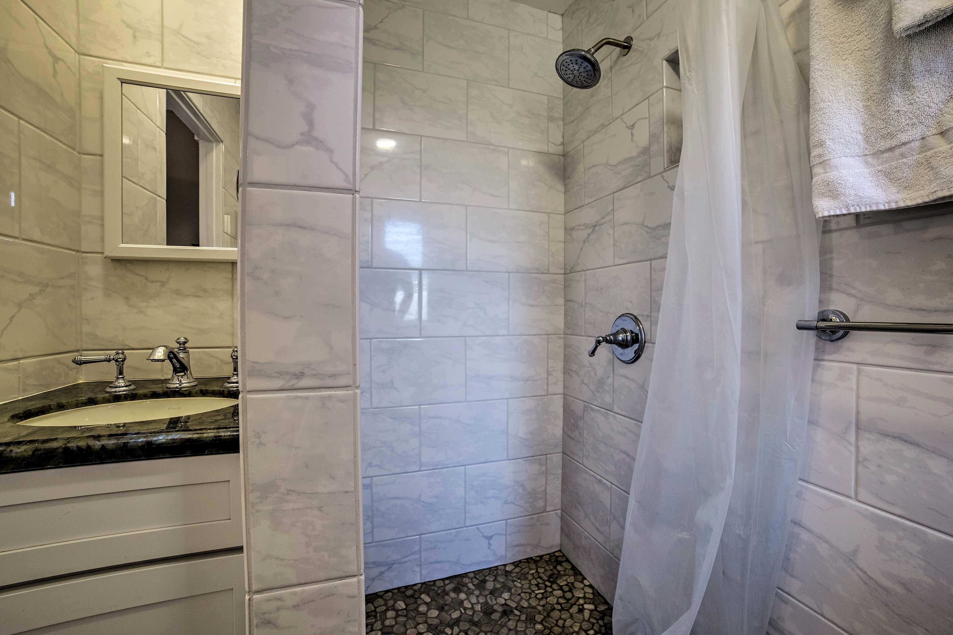 A bathroom with a marble sink, a shower with a curtain, and a mirror.