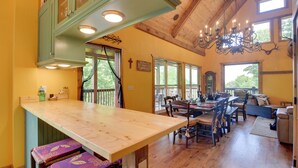 Une cuisine spacieuse dotée de plans de travail en bois, un coin repas avec une grande table et des chaises, et un coin salon confortable avec un canapé et des coussins.