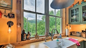 Une cuisine dotée d’une grande fenêtre, de plans de travail en bois, d’un évier et de divers ustensiles de cuisine.