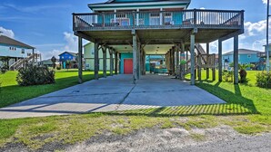 A beachfront house with a balcony, a concrete walkway, and a grassy area.
