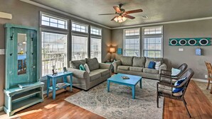 A living room with two sofas, a coffee table, a side table, a wicker chair, and a ceiling fan.