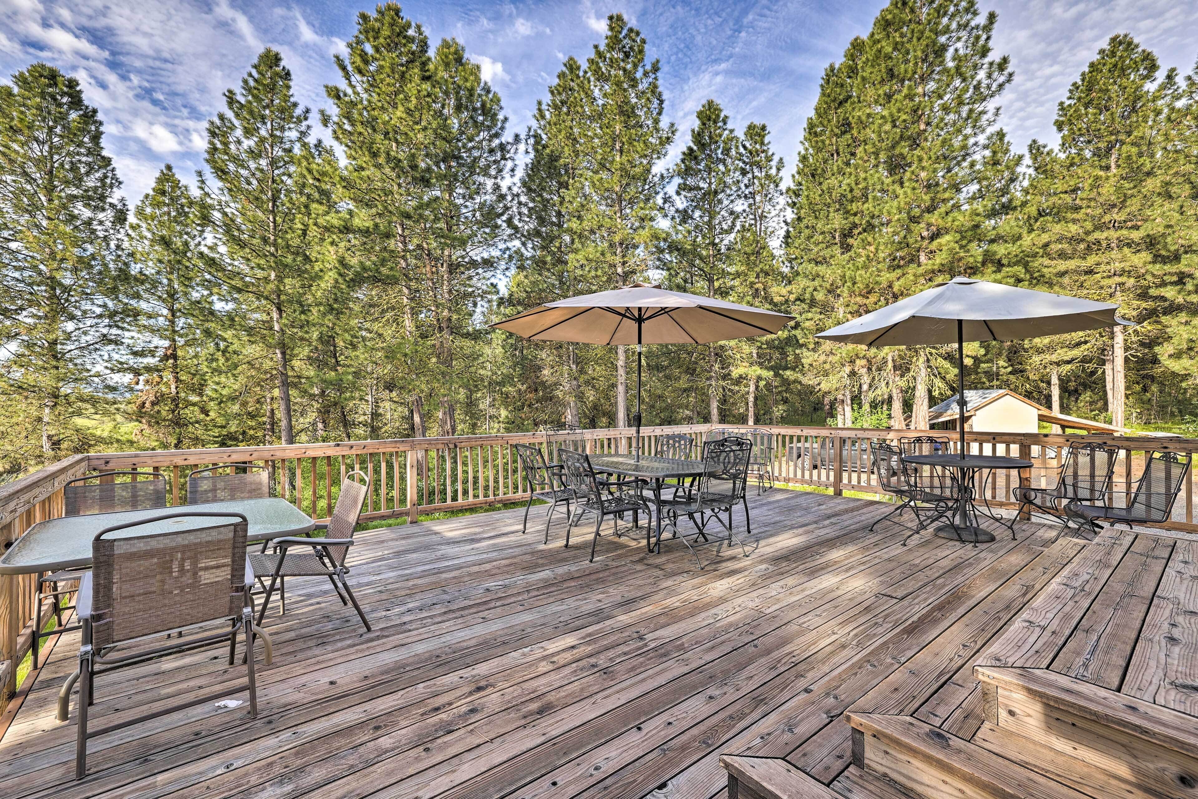 A wooden deck with outdoor furniture, including a table and chairs, and two umbrellas.