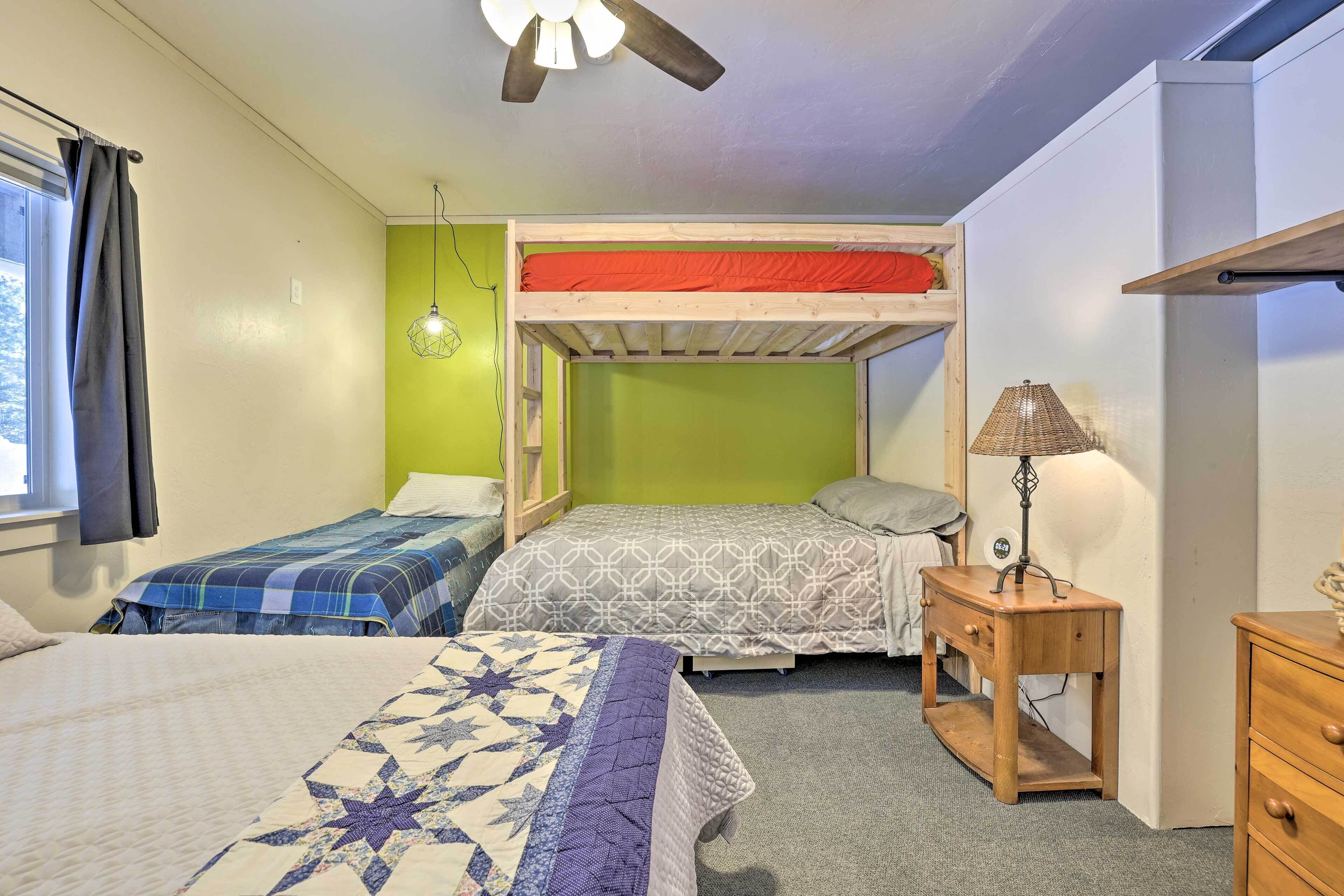 A dorm-style room with bunk beds, a small wooden nightstand, and a lamp.
